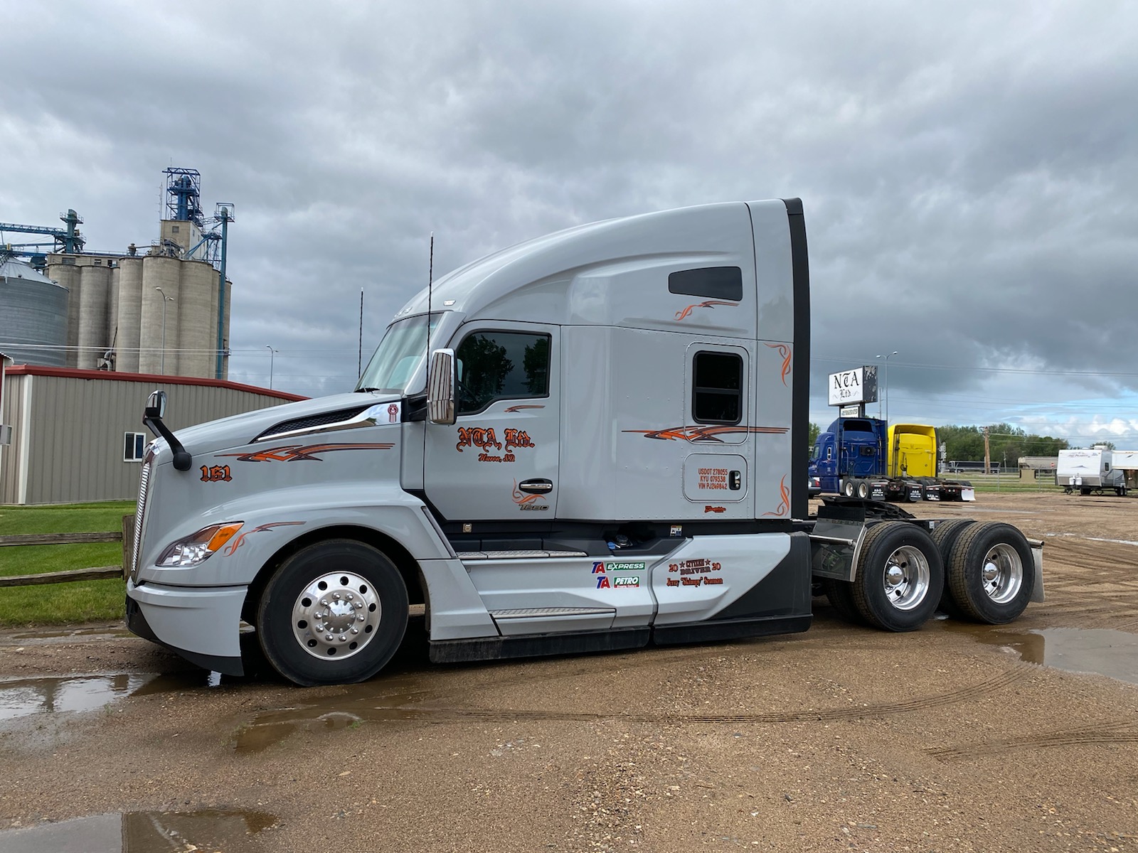 Gray semi truck parked near grain silos