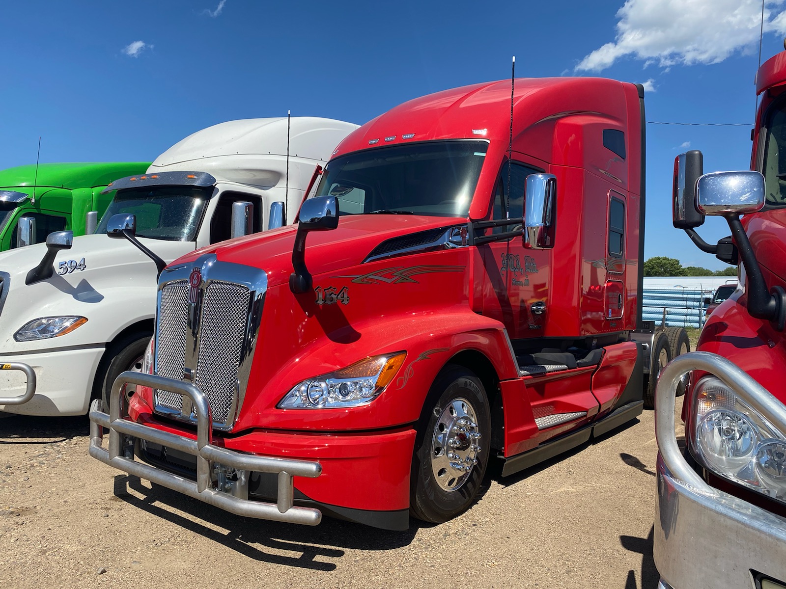 Red semi truck parked beside other trucks