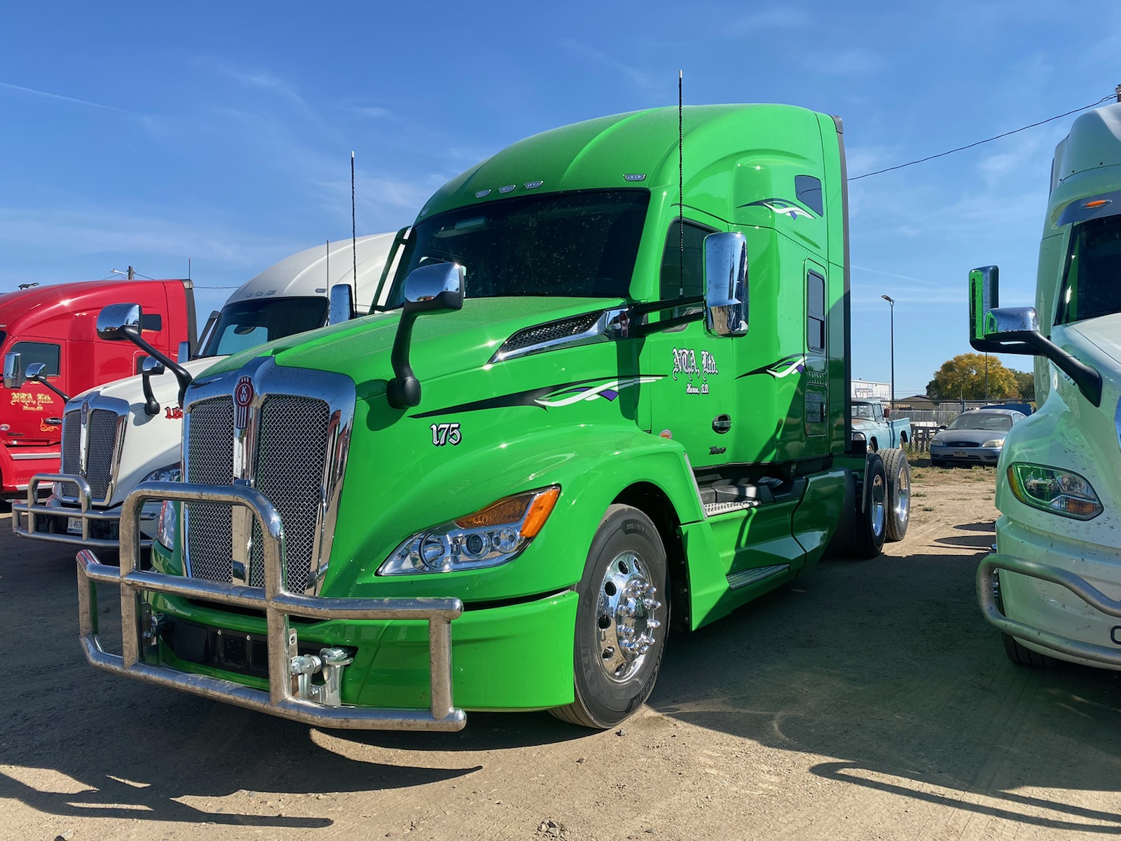 Green semi truck parked among other trucks