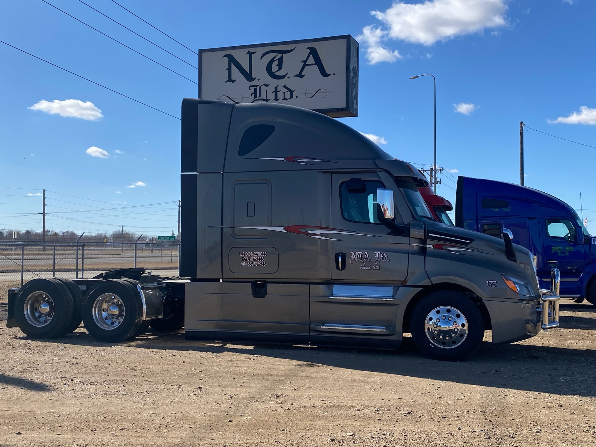 Gray semi truck tractor parked under NCA sign